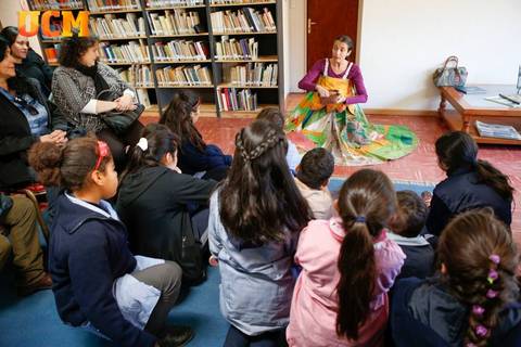 Una narradora cuenta historias a un grupo de niños en una biblioteca.