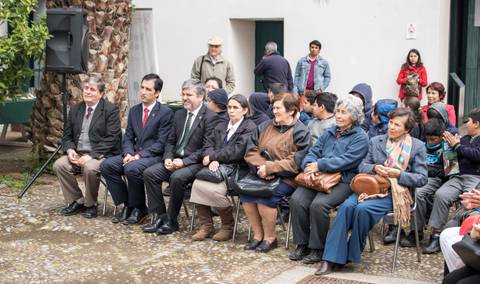 Un grupo de personas sentadas en una reunión al aire libre.