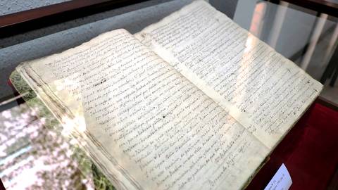 El libro antiguo abierto muestra páginas llenas de texto manuscrito.