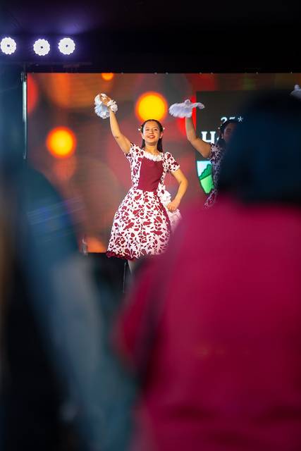 Una bailarina con un vestido colorido realiza una presentación en un escenario iluminado.