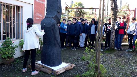 Un grupo de niños observa una escultura en un jardín.