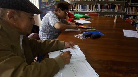 Un grupo de personas mayores participa en una actividad de aprendizaje en una biblioteca.