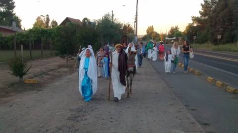 Un grupo de personas vestidas con trajes tradicionales camina por la calle al atardecer.