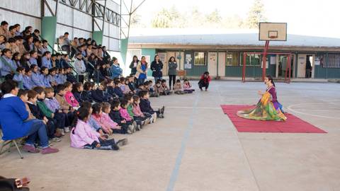 Una artista se presenta frente a un público de niños en un gimnasio escolar.