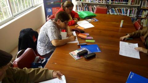 Un grupo de personas trabaja en una mesa en un ambiente de biblioteca.