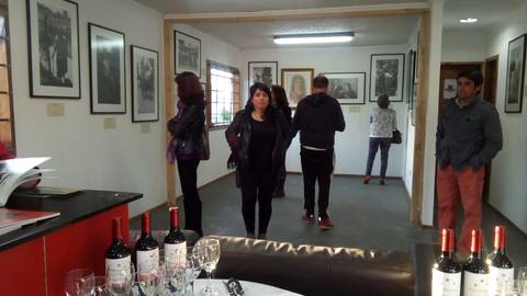 Una galería de arte con varias personas observando fotografías enmarcadas en las paredes.