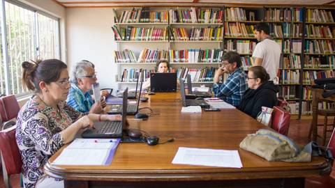 Un grupo de personas trabaja en una biblioteca utilizando computadoras portátiles.