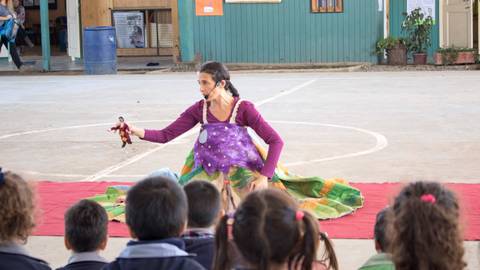 Una actriz de teatro presenta una obra mientras los niños la observan atentamente.
