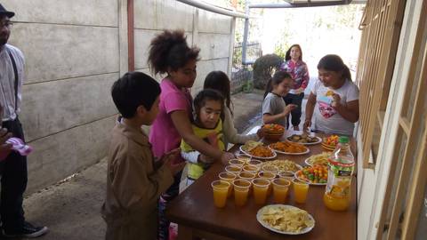 Un grupo de niños disfrutando de una merienda al aire libre con varios tipos de comida y bebidas.