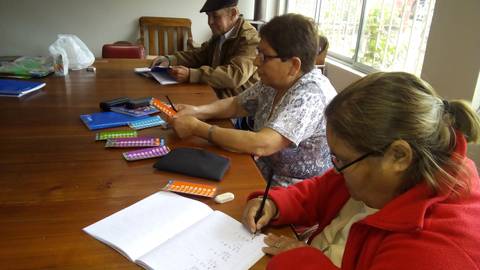 Un grupo de personas mayores está aprendiendo y escribiendo en un aula.