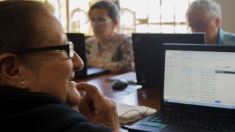 Un grupo de personas mayores aprende a usar computadoras en un aula.