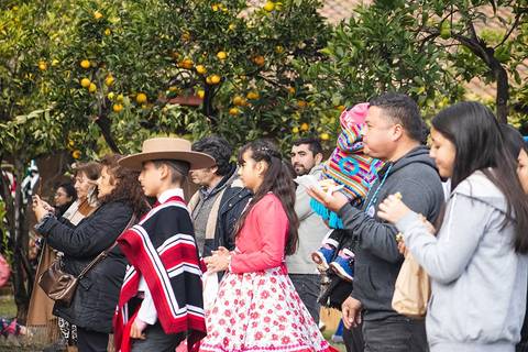 Un grupo de personas vestidas con trajes típicos observa un evento cultural en un ambiente festivo.