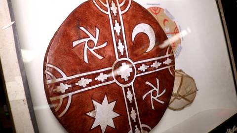 La imagen muestra un tambor decorado con símbolos en colores rojo y blanco.