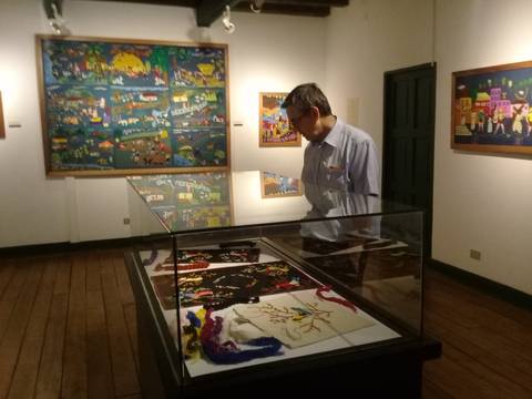 Un hombre observa obras de arte en una galería iluminada.