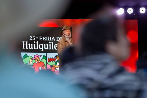 Un hombre vestido con sombrero y abrigo habla en un evento en la Feria de Huilquilemu.