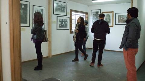 Un grupo de personas observa fotografías en una galería de arte.