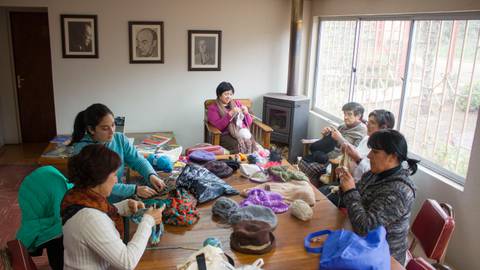 Un grupo de mujeres sentadas alrededor de una mesa, trabajando en manualidades.