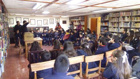 Un grupo de estudiantes escucha atentamente a un orador en una biblioteca.