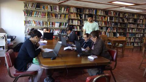 Un grupo de personas trabajando en una biblioteca frente a sus computadoras portátiles.