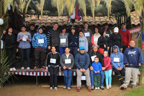 Un grupo de personas se reúne en un escenario al aire libre bajo una carpa, sonriendo y posando para la foto.