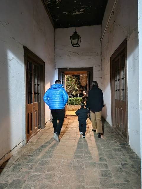 Tres personas caminando por un pasillo hacia una salida iluminada.