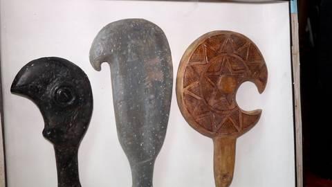 Tres objetos de arte tallados, cada uno con un diseño distintivo y de diferentes colores.