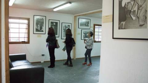 Tres personas observan fotografías en una galería.