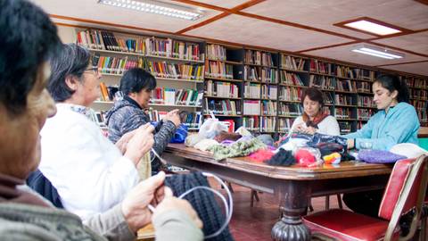 Un grupo de mujeres se reúne en una biblioteca para tejer y compartir conocimientos.