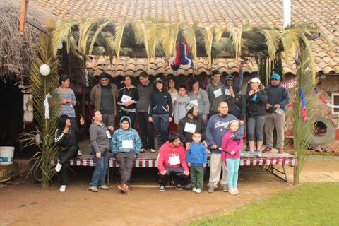 Un grupo de personas posando en un escenario decorado con palmas y banderas.