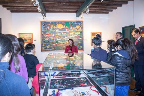 Una guía está explicando sobre las obras de arte en un museo mientras un grupo de personas escucha atentamente.