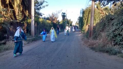 Un grupo de personas camina por un camino polvoriento en un entorno rural.