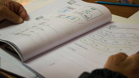 Una persona examina un cuaderno abierto con ejercicios y dibujos relacionados con el aprendizaje.