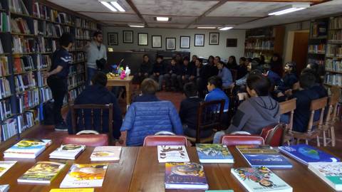 Una reunión en una biblioteca con un grupo de personas escuchando a un orador.