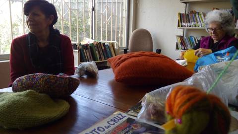 Dos mujeres están sentadas alrededor de una mesa, trabajando en manualidades con hilo y lana.