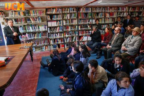 Una presentación en una biblioteca con un orador y un público atento.