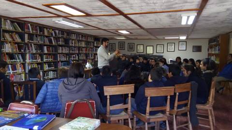 Un grupo de estudiantes escucha atentamente a un instructor en una biblioteca.