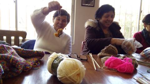 Un grupo de mujeres se reúne para realizar manualidades con hilo de diversos colores.