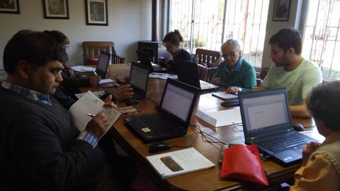 Un grupo de personas trabajando en un taller frente a computadoras portátiles en una mesa de trabajo.