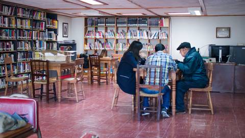 Una biblioteca con mesas de estudio y estanterías llenas de libros.