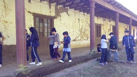 Grupo de estudiantes se encuentran en un patio con paredes desgastadas en un edificio antiguo.