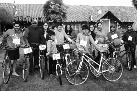 Un grupo de personas sonríe junto a bicicletas en un entorno al aire libre.