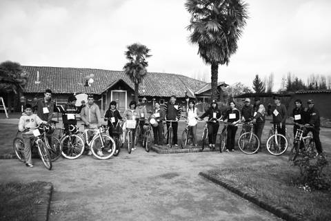 Un grupo de personas posando en un paisaje en blanco y negro, todas con bicicletas.