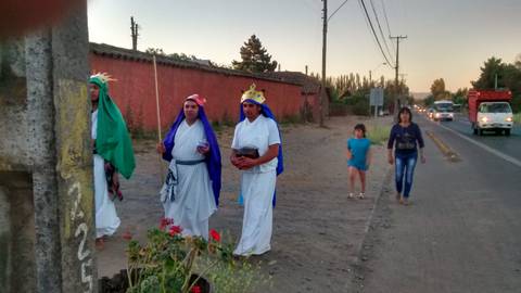 Un grupo de personas vestidas con trajes tradicionales caminan por una calle al atardecer.