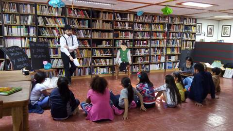 Un narrador cuenta historias a un grupo de niños en una biblioteca.