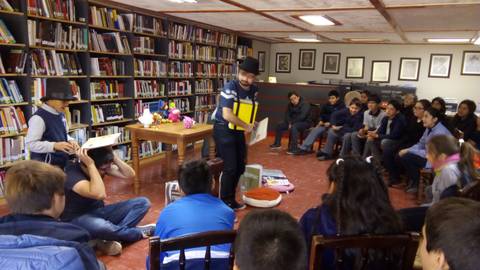 Un grupo de niños observa atentamente una actividad de cuentacuentos en una biblioteca.