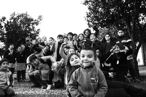 Un grupo de niños sonrientes posa juntos al aire libre.