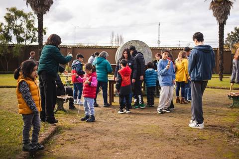 Un grupo de niños y adultos están reunidos en un parque, participando en actividades al aire libre.