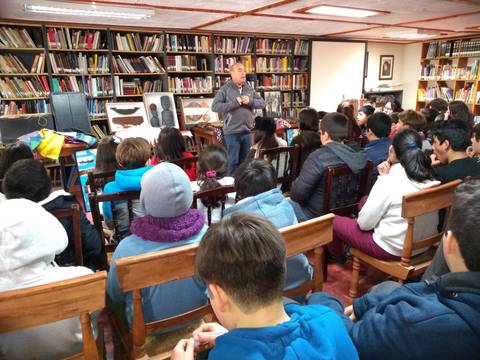 Un grupo de estudiantes escucha atentamente a un ponente en una biblioteca.