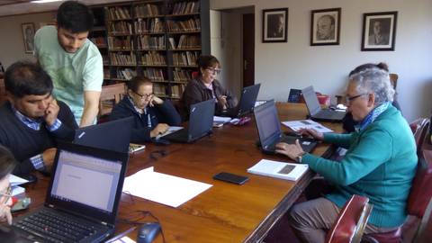 Un grupo de personas trabajando en laptops alrededor de una mesa en un ambiente de aprendizaje.