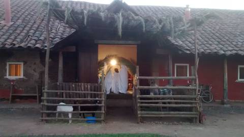 Una casa tradicional con una entrada iluminada, rodeada de naturaleza y estructuras de madera.